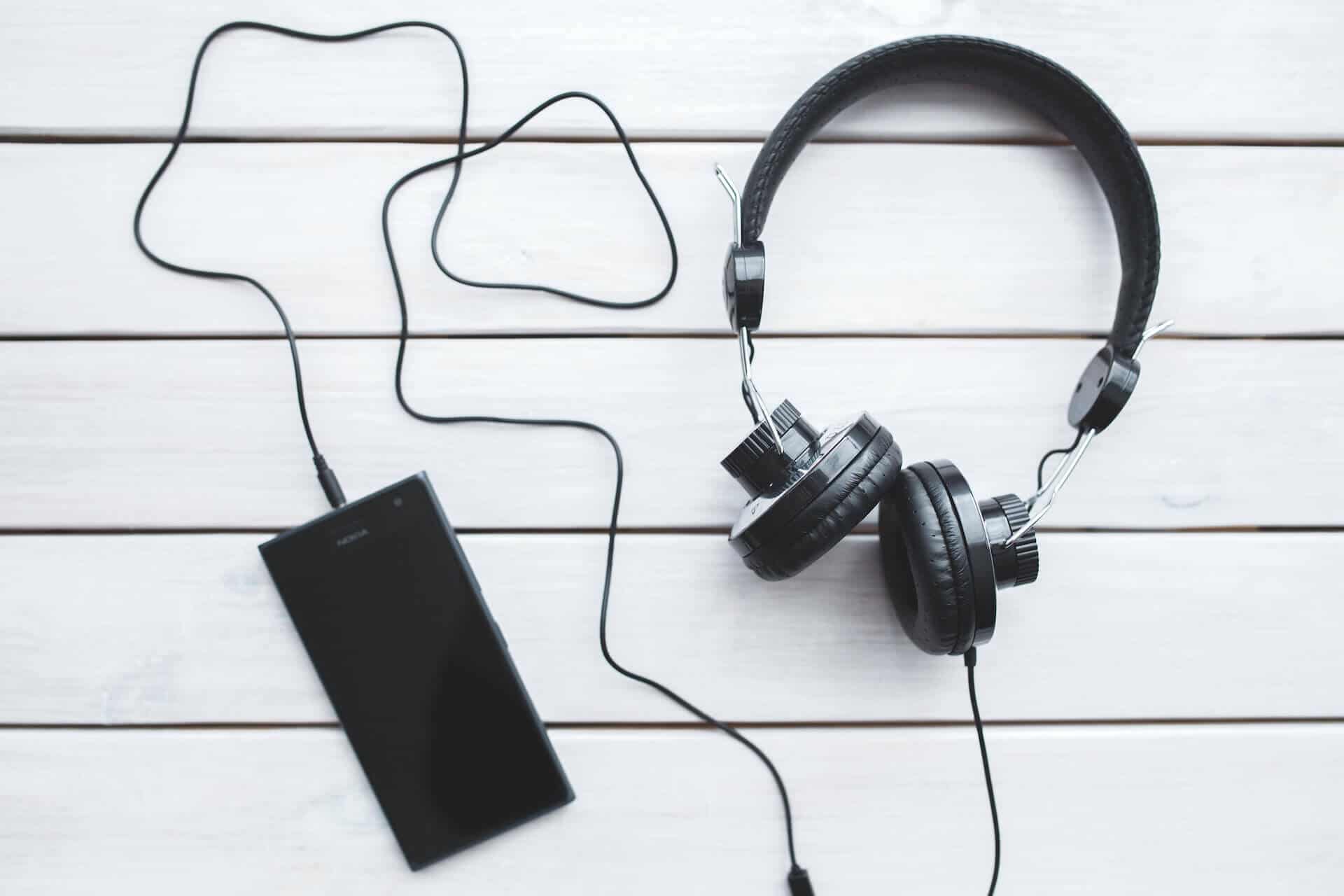 Smartphone auf Tisch mit Audiokabel und Kopfhörer