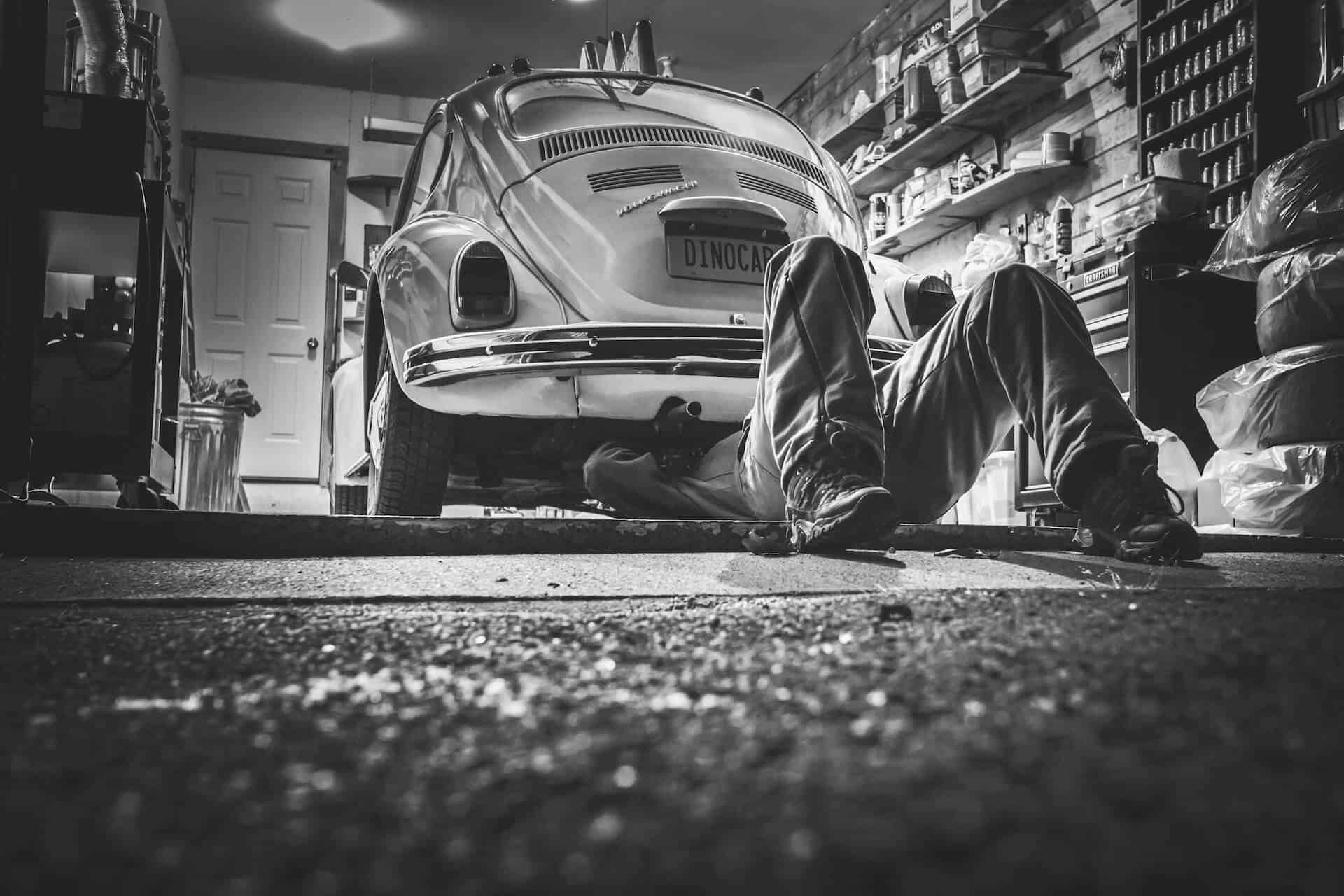Mann in Autowerkstatt checkt Auto