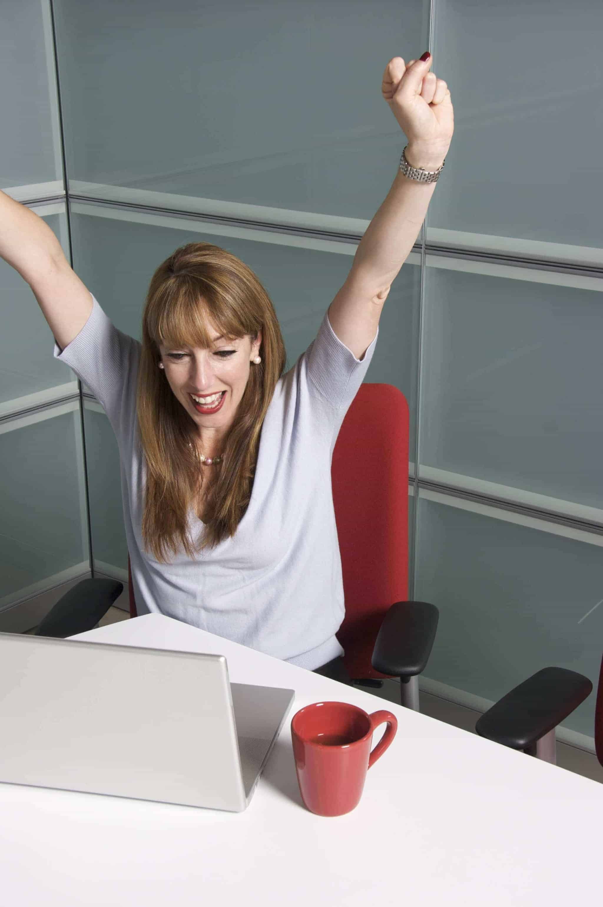 Frau im Büro freut sich, vermutlich über einen lizenzfreien Download