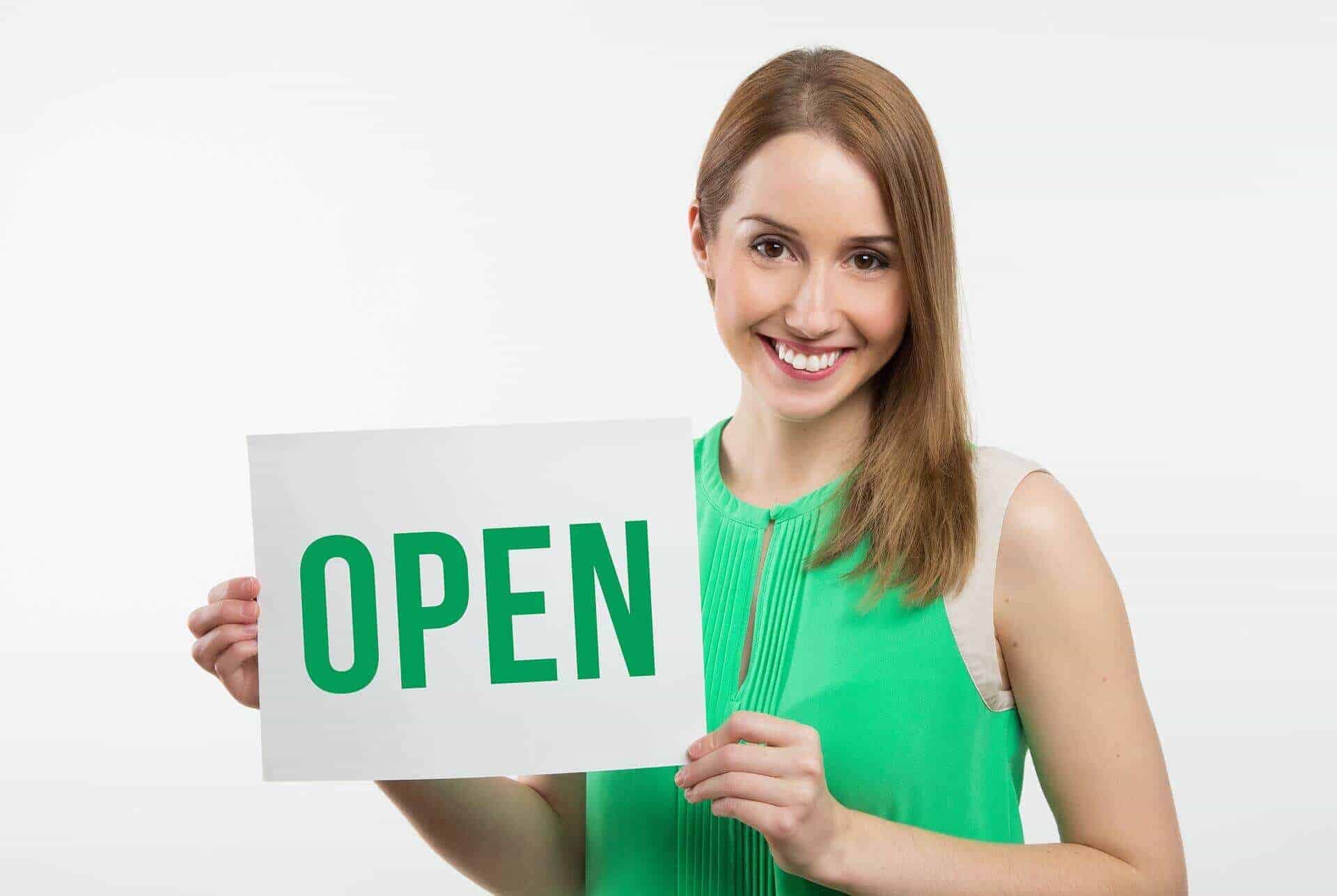 Frau hält auf lizenzfreiem Bild ein Schild mit der Beschriftung "Open"