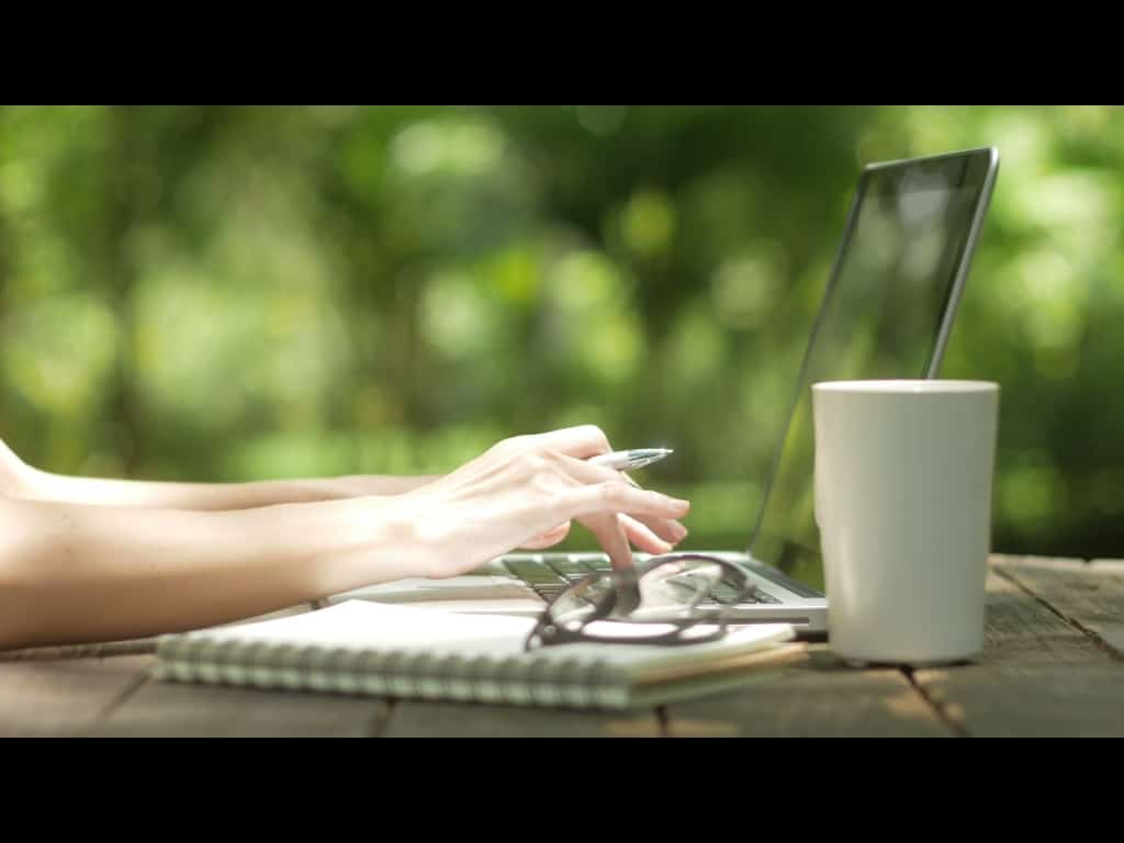 Person arbeitet an einem Notebook im Garten